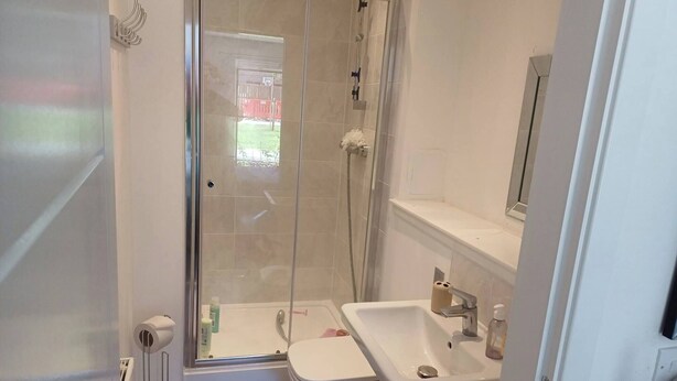Une salle de bain avec une douche à parois de verre, des toilettes et un lavabo.
