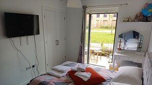 Une chambre à coucher comprenant un lit, un téléviseur fixé au mur, une armoire et une fenêtre donnant sur l’extérieur.