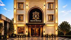 A hotel with a checkered entrance, a prominent logo above the entrance, and a well-lit facade.