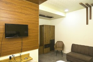 Habitación con televisión de pantalla plana montada en una pared de madera, un armario, un sillón de cuero marrón y un sofá marrón.