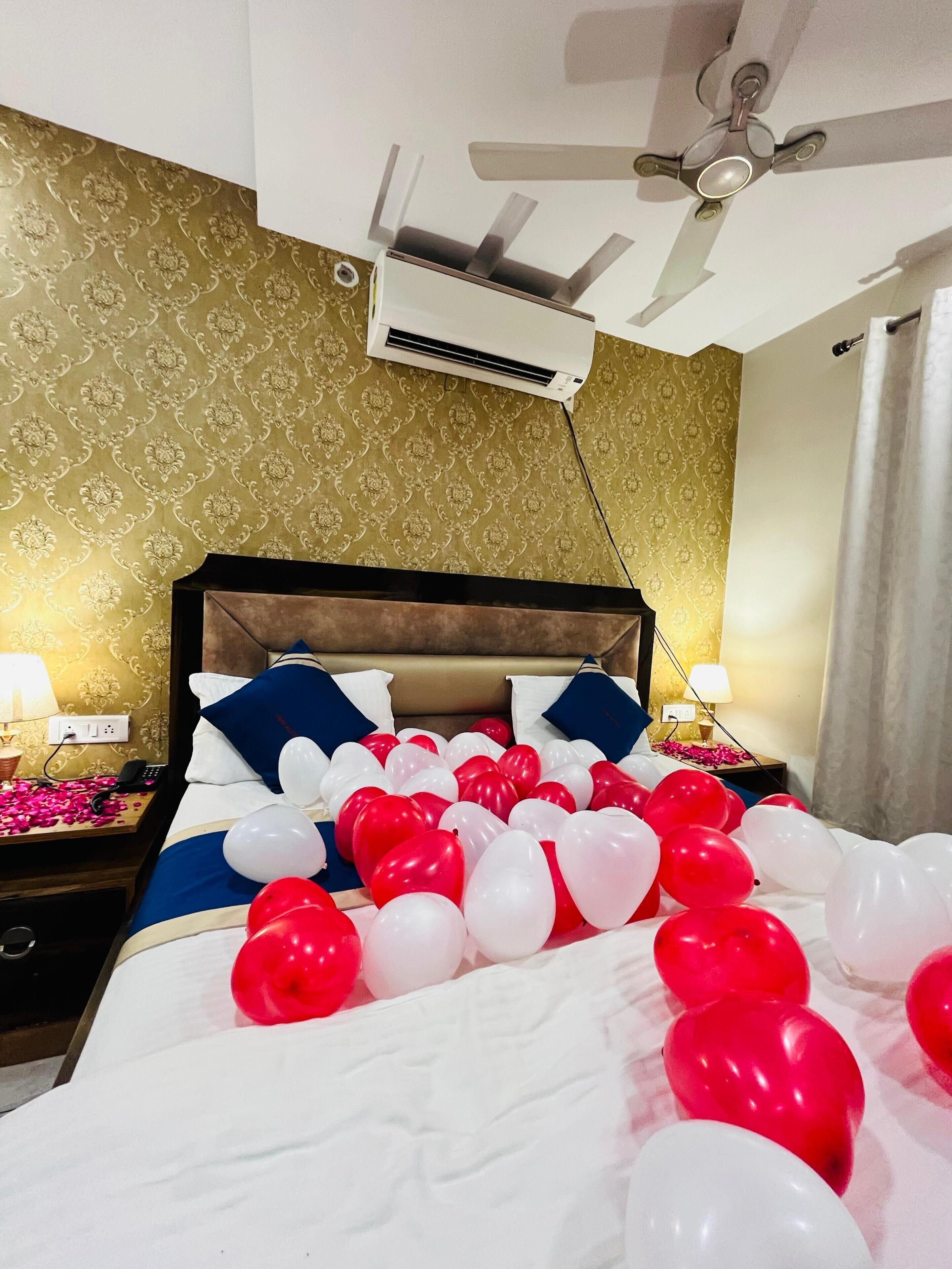 Una habitación de hotel con cama, ventilador de techo, aire acondicionado y una mesita de noche con lámpara.