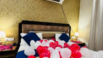 Una habitación de hotel con cama, ventilador de techo, aire acondicionado y una mesita de noche con lámpara.