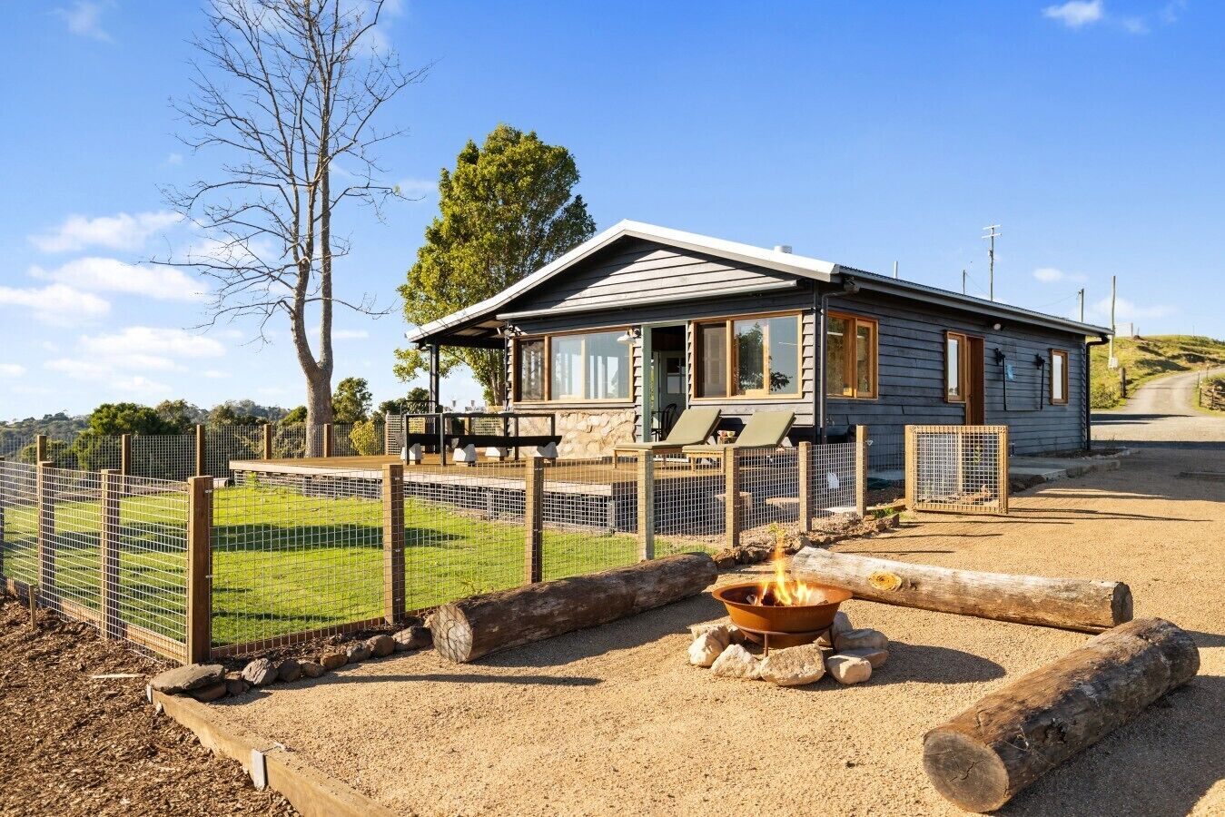 A lodge with a fenced outdoor area, a fire pit, and a view of the surrounding landscape.