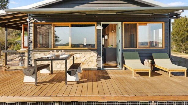 Una casa moderna con terraza, mobiliario exterior y ventanas amplias.