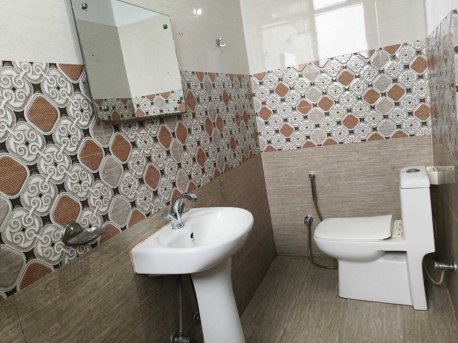 A bathroom with a sink, toilet, and decorative tiled walls.