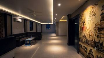 Un vestíbulo de hotel con una recepción, zona de estar y un mural de un edificio histórico.