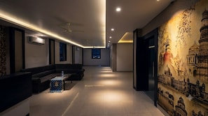 A hotel lobby with a reception desk, seating area, and a mural of a historical building. - Karma Bodhgaya (Bodh Gaya)