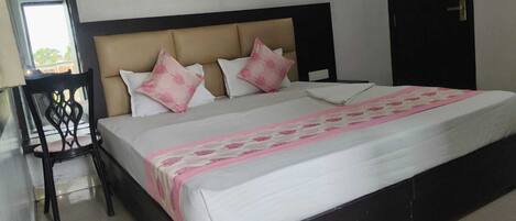 A hotel room with a bed, a chair, a wardrobe, and a mirror.