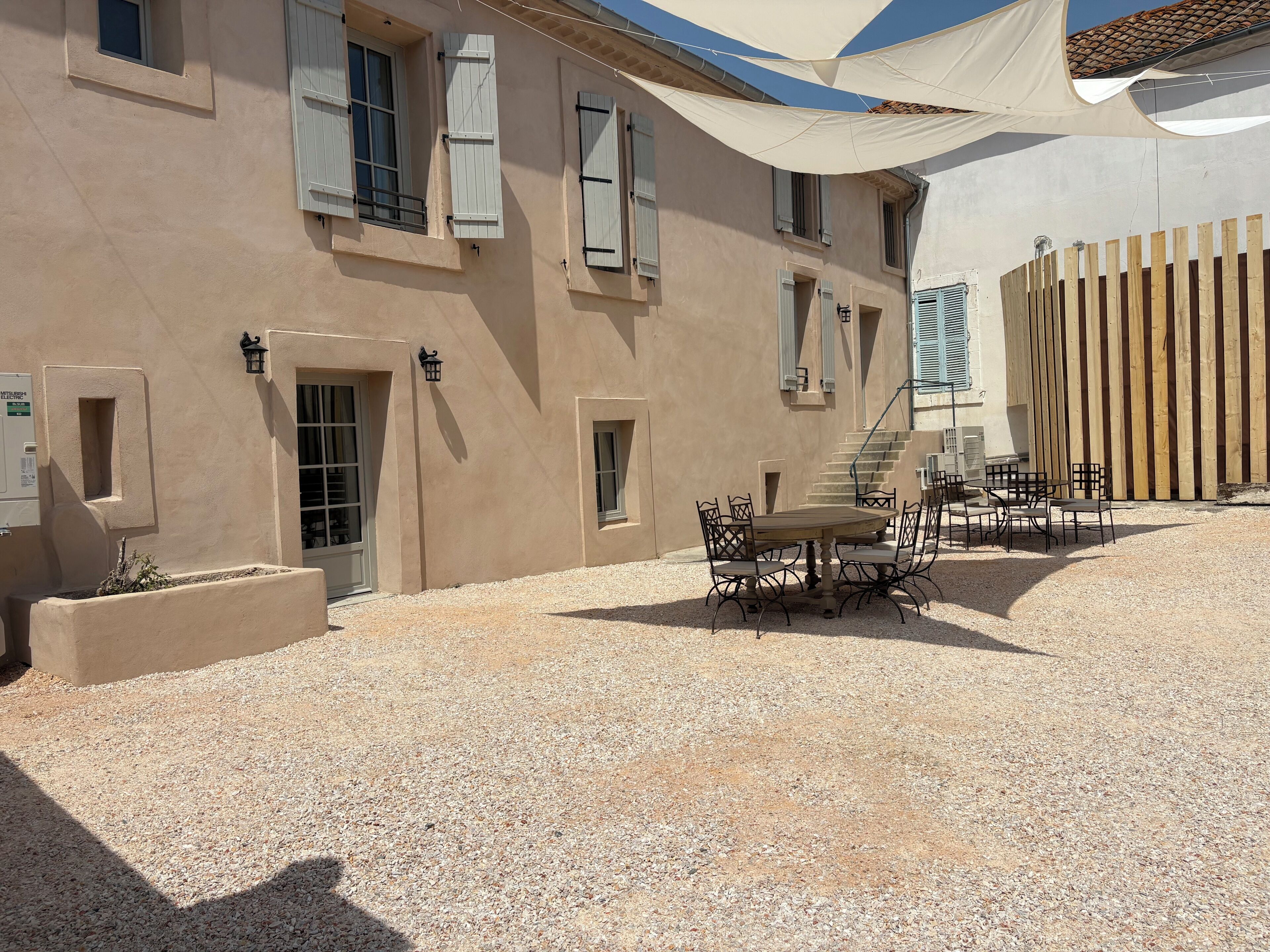 A building with a gravel courtyard, outdoor seating, and a wooden fence.