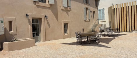 A building with a gravel courtyard, outdoor seating, and a wooden fence.