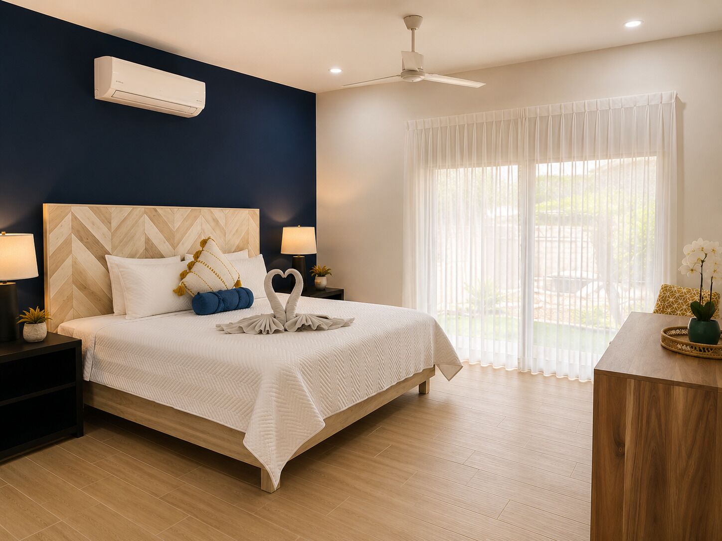 Een hotelkamer met een bed, nachtkastjes, een plafondventilator en een raam met gordijnen.