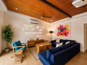 A modern living room with a blue sofa, wooden coffee table, and a ceiling fan. - Dream House 20 Min from Tamarindo Beach (Guanacaste)