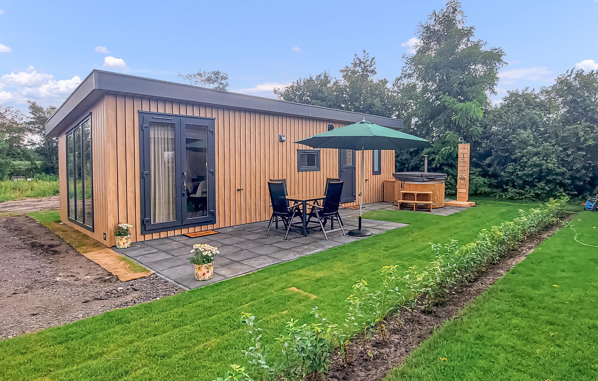 Une cabane moderne en bois, dotée d’une terrasse, d’un jacuzzi et d’un petit jardin.