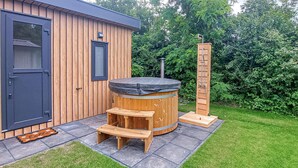 Eine Holzhütte mit Whirlpool, einer Holzleiter und einer Sitzbank.