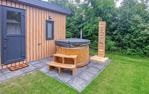 Eine Holzhütte mit Whirlpool, einer Holzleiter und einer Sitzbank.
