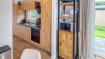 Une cuisine moderne avec des meubles de rangement en bois, un four encastré et une fenêtre donnant sur un jardin.