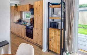 Eine moderne Küche mit Holzschränken, einem Einbauofen und einem Fenster mit Blick auf einen Garten.