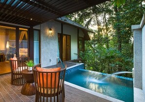 A pool area with a hot tub, surrounded by lush greenery.