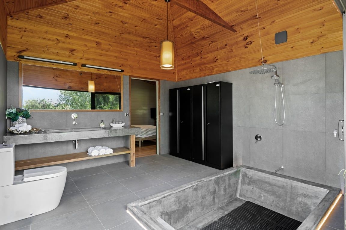 Une salle de bain moderne avec un plafond en bois, un grand miroir, une baignoire et un espace douche.
