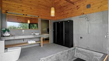 Une salle de bain moderne avec un plafond en bois, un grand miroir, une baignoire et un espace douche.