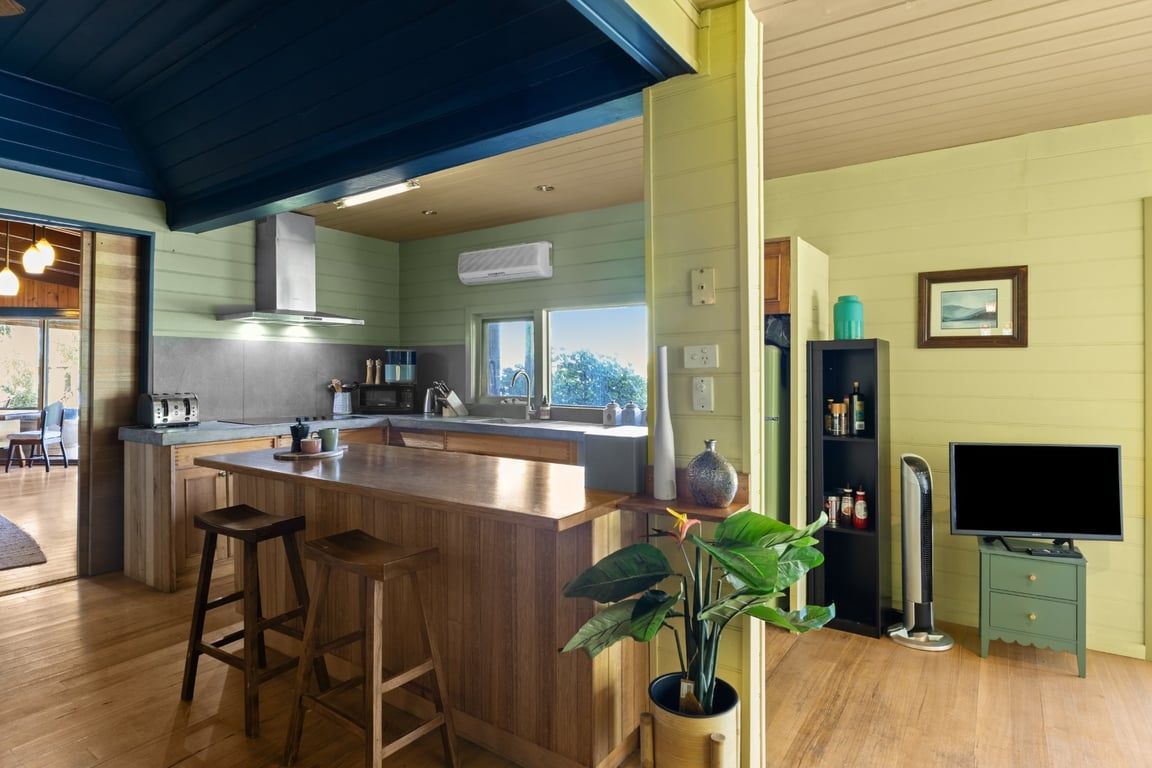 Une cuisine moderne dotée d’un îlot central, de tabourets de bar, d’une cuisinière intégrée et d’une grande fenêtre.