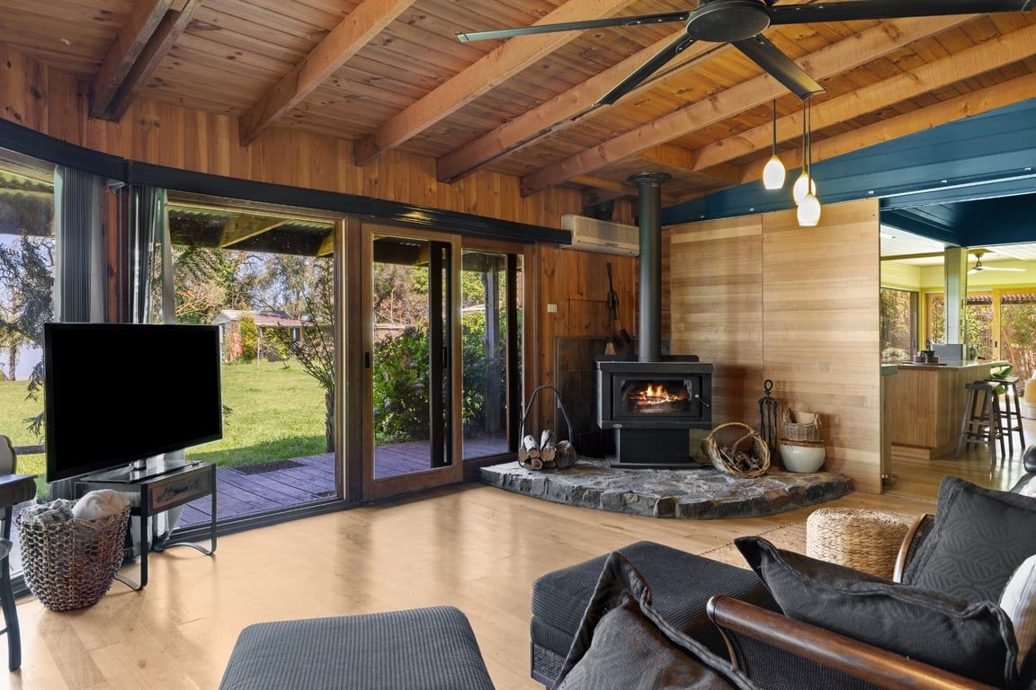 Una sala de estar moderna con chimenea, televisor y ventana grande con vistas a un jardín.
