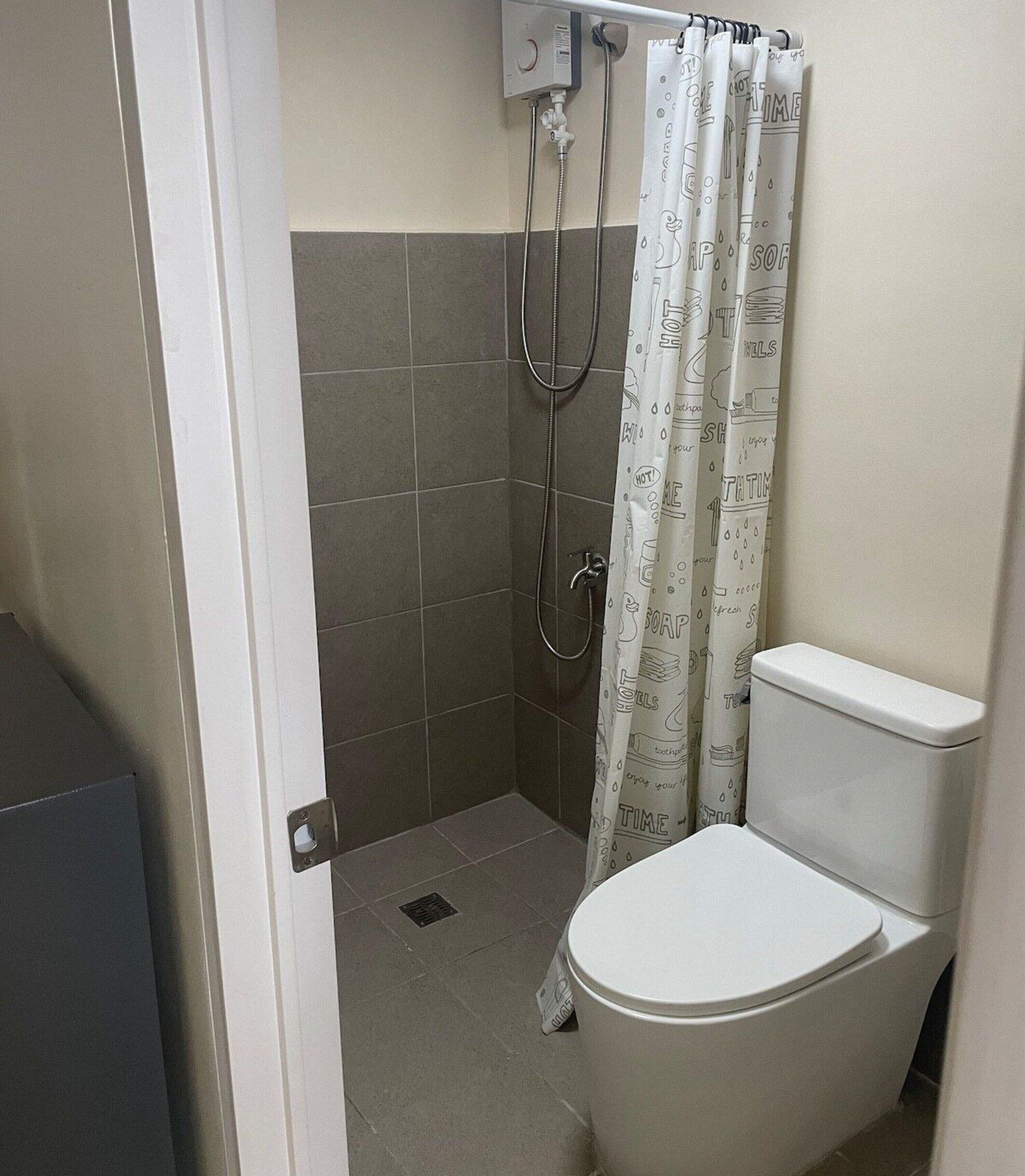 A bathroom with a shower, toilet, and a towel rack.