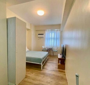 A narrow hallway leading to a bedroom with a bed, a small table, and a chair. - Cozy Retreat by Jane at Balai (Lapu-Lapu)