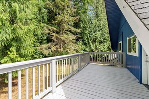 A wooden deck with a white railing, leading to a building with blue siding.