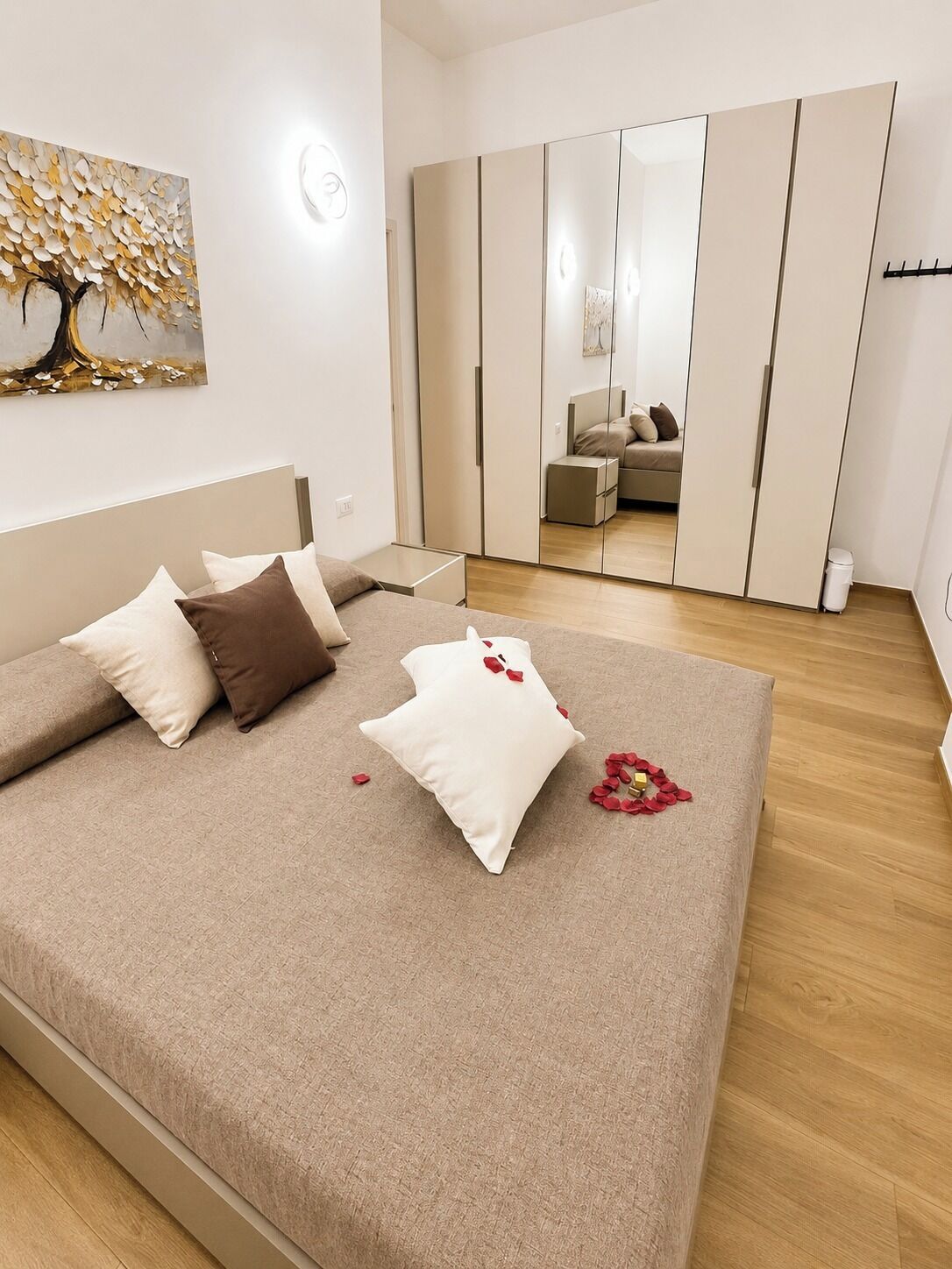 Un dormitorio con cama, almohadas, mesita de noche, armario y un cuadro en la pared.