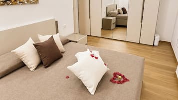 A bedroom with a bed, pillows, a bedside table, a wardrobe, and a painting on the wall.