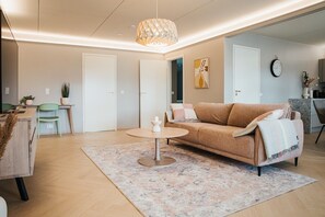 Un salon moderne avec un canapé, une table basse et un luminaire suspendu.