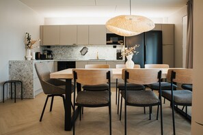 Une cuisine moderne avec un coin repas, comprenant un grand îlot central, des chaises contemporaines et un luminaire suspendu.