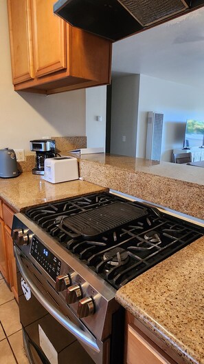 A kitchen with a stainless steel stove, a toaster, and a coffee maker on the countertop. - Beautiful 2-bedroom condo with AC in soothing long Beach. (Long Beach)