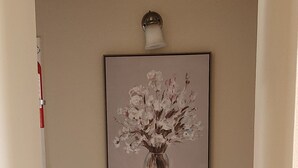 Un corridoio con un quadro raffigurante un vaso di fiori appeso al muro.