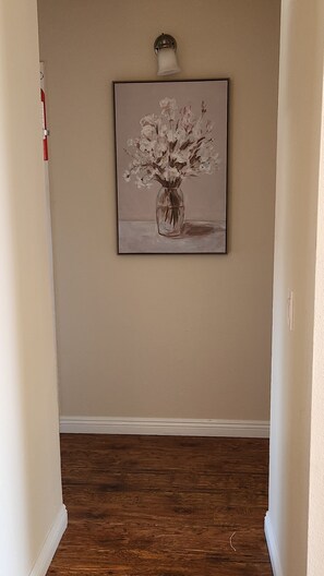 Een gang met een schilderij van een vaas met bloemen aan de muur.