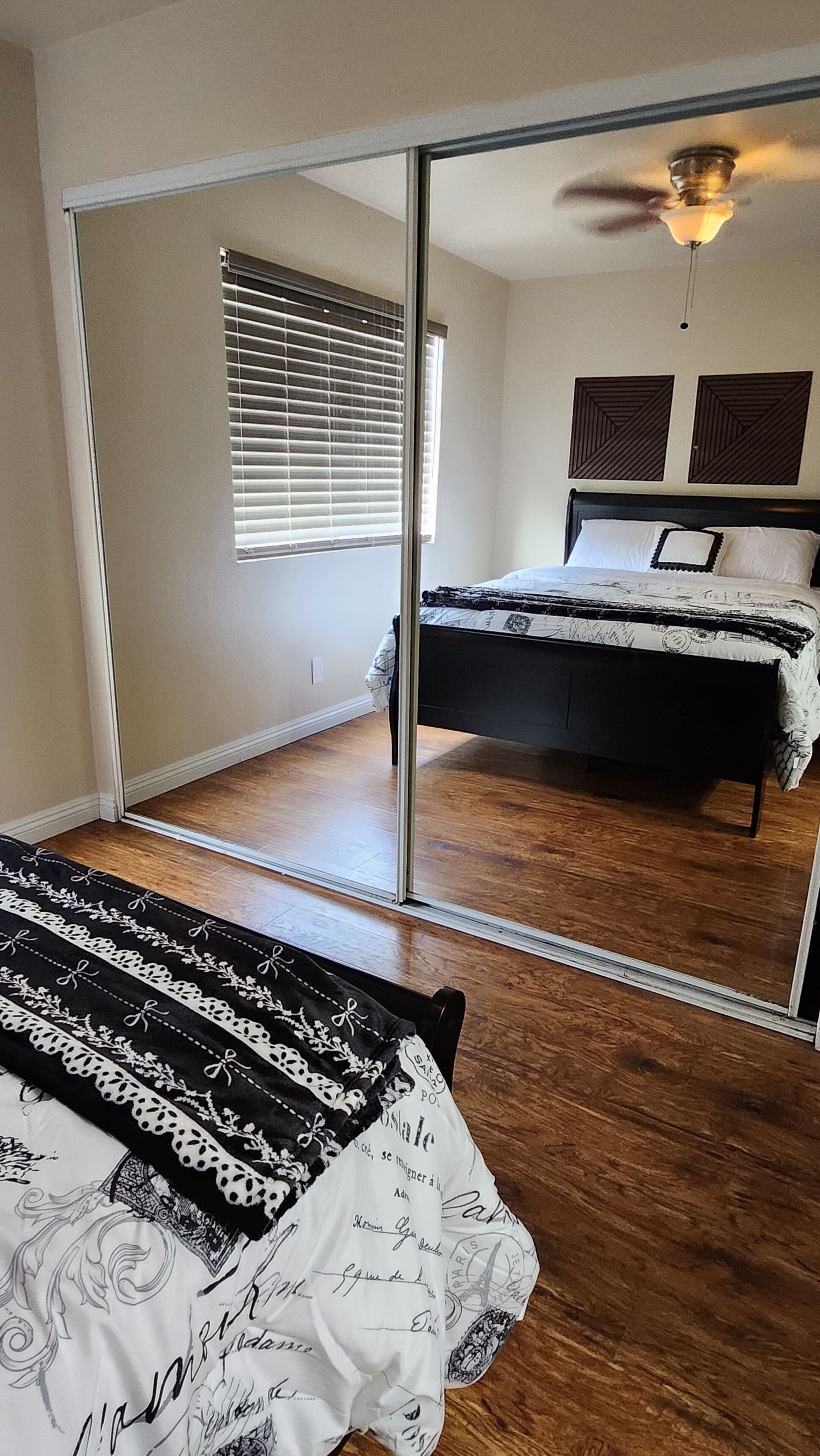 A bedroom with a bed, a sliding glass door, a ceiling fan, and a window with blinds.