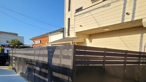Un edificio con facciata beige, recinzione in metallo nero e marciapiede lastricato.