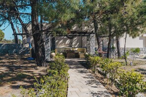 Ein gepflasterter Weg führt zu einem Steinkamin, über dem eine Pergola angebracht ist.