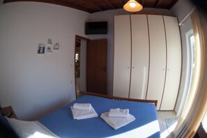 Ein Schlafzimmer mit Bett, Kleiderschrank und einer Tür zu einem weiteren Raum.