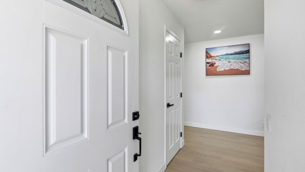 A hallway with white doors and a painting of a beach scene on the wall.