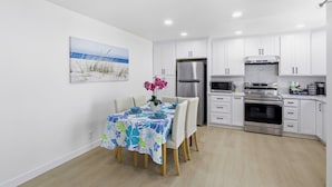 A modern kitchen with white cabinets, a stainless steel refrigerator, an oven, and a microwave.