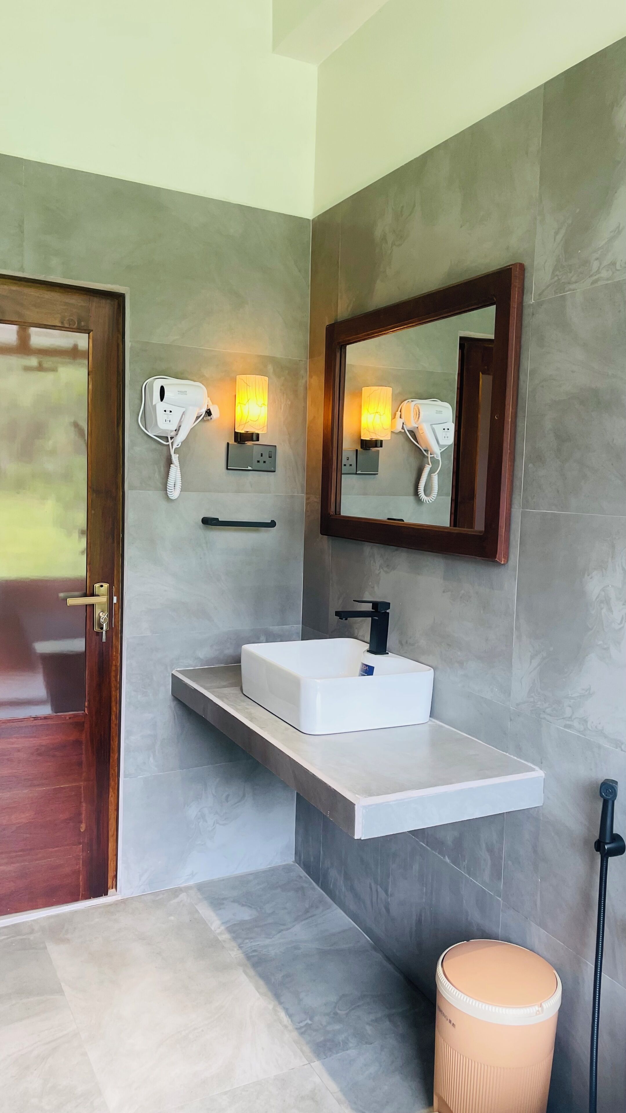 Une salle de bain avec un lavabo blanc, un miroir et deux sèche-cheveux fixés au mur.