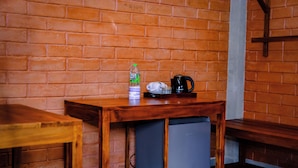 A compact kitchenette with a small refrigerator, a coffee maker, and a water bottle on a wooden table.