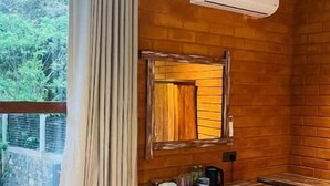 A room with a sofa, a small table, a mirror, and an air conditioning unit.