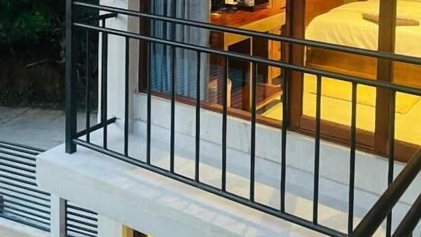 A room with a bed, a window, and a balcony with a railing.