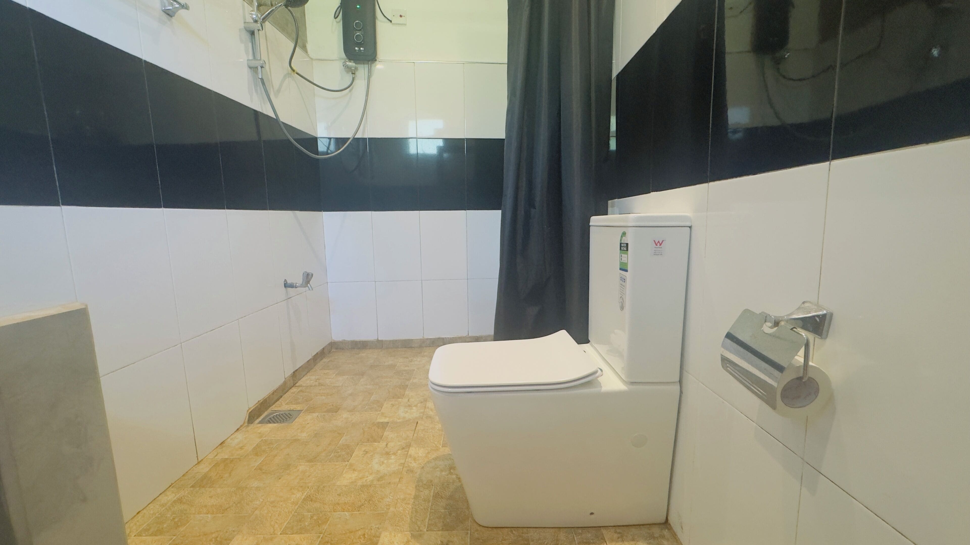 Een badkamer met toilet, douche en boiler.