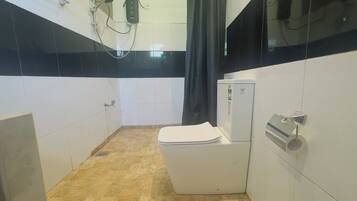 Een badkamer met toilet, douche en boiler.