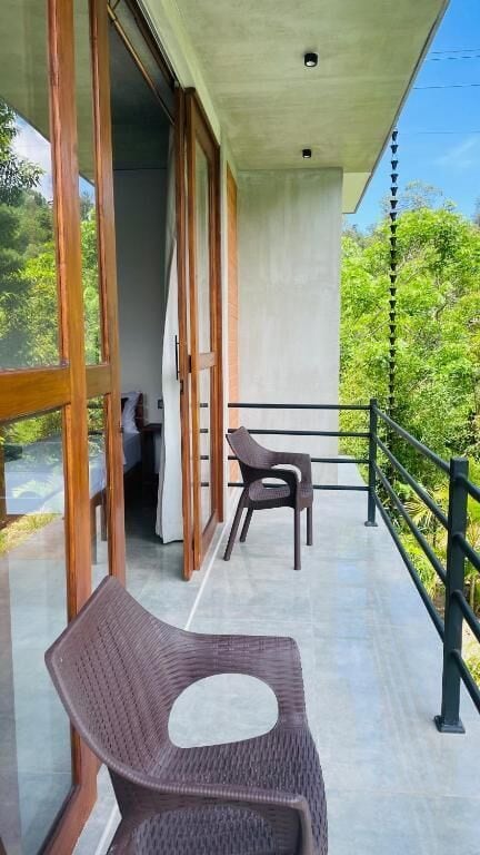 Un balcone con una sedia in vimini, un tavolo e vista sul verde.