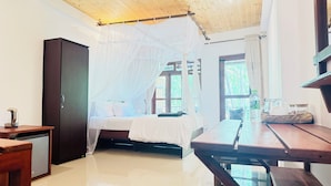 A room with a bed under a canopy, a wooden desk, a small table, and a wardrobe.